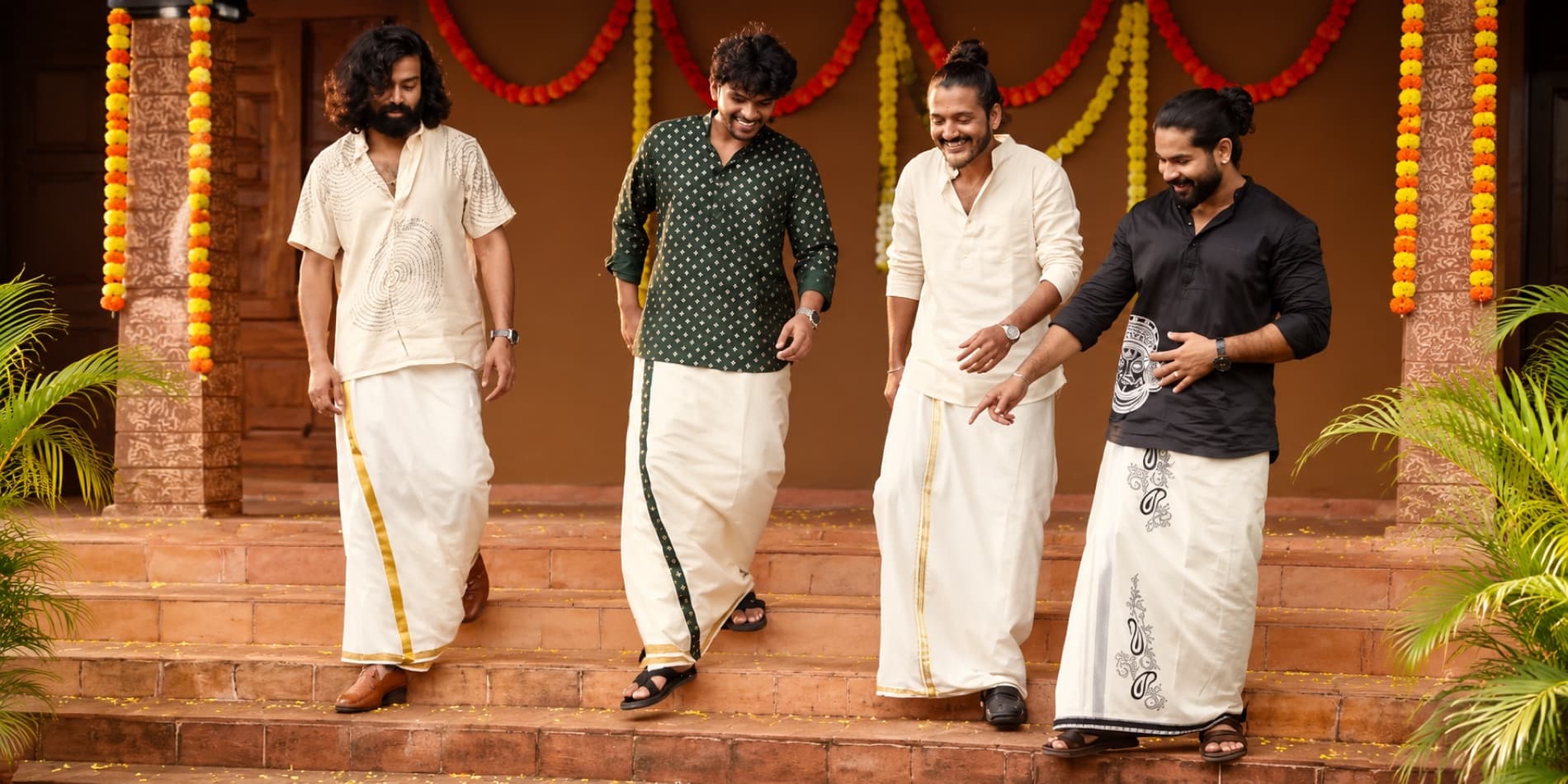 Four men in traditional kurtas and mundus walking down festive steps
